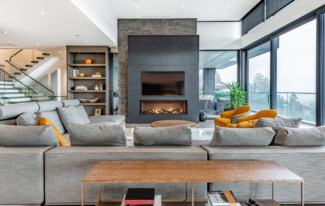 Linear gas fireplace in a dark stone media wall in a modern great room